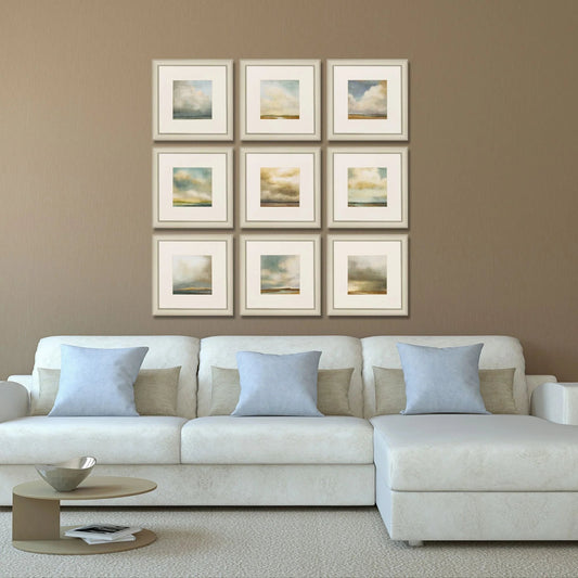 White sofa with decorative pillows against a wall with framed artwork