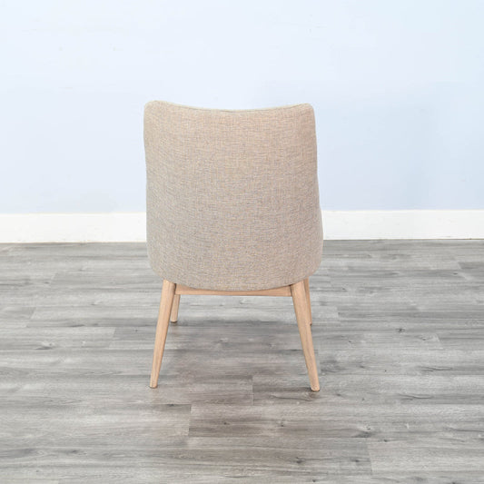 Beige armchair on a wooden floor with a light blue wall background