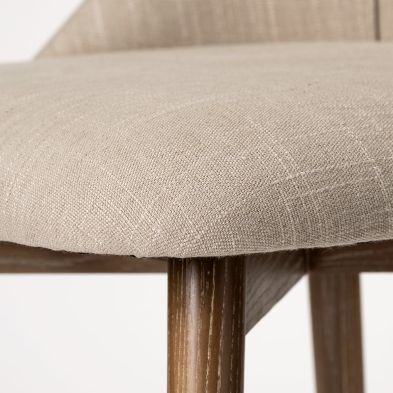 Close-up of a chair with beige fabric seat and wooden legs on a white background