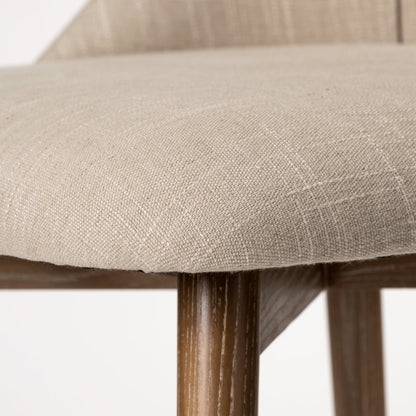 Close-up of a chair with beige fabric seat and wooden legs on a white background