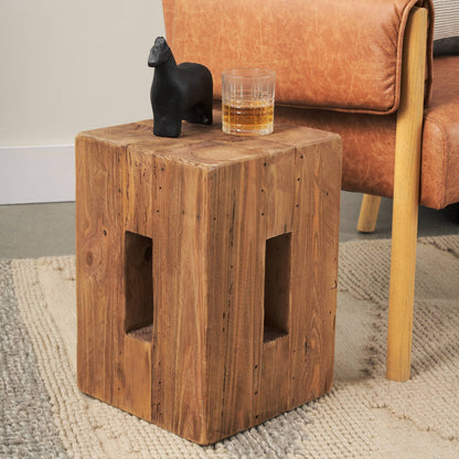 Wooden side table with a glass of whiskey and a black figurine next to a brown leather chair.